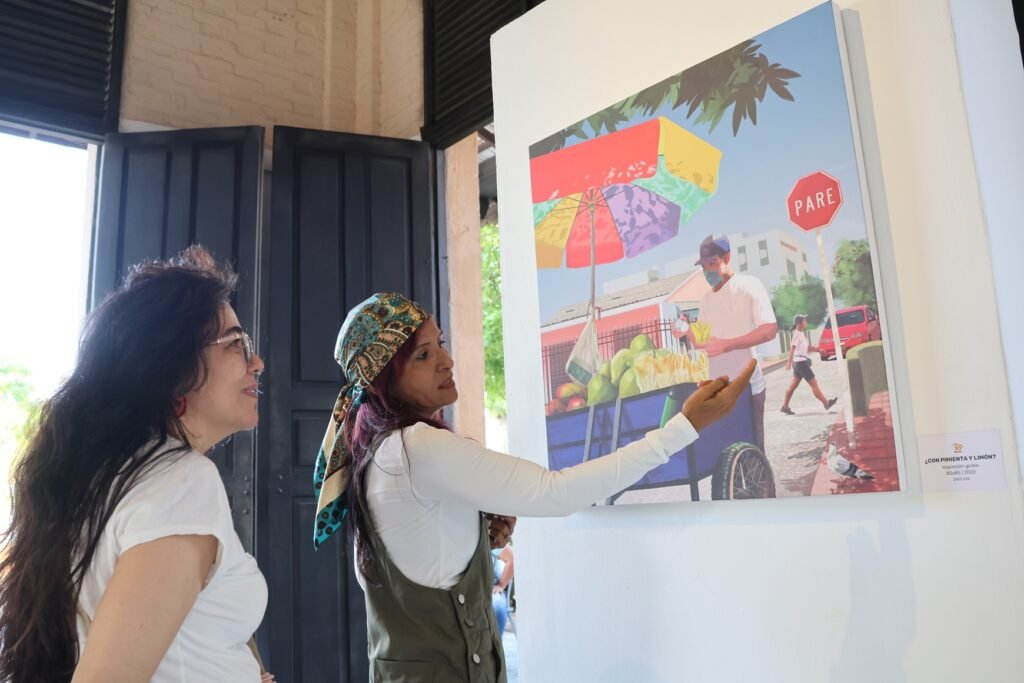 Mónica Vega explica su obra a una visitante de la exposición